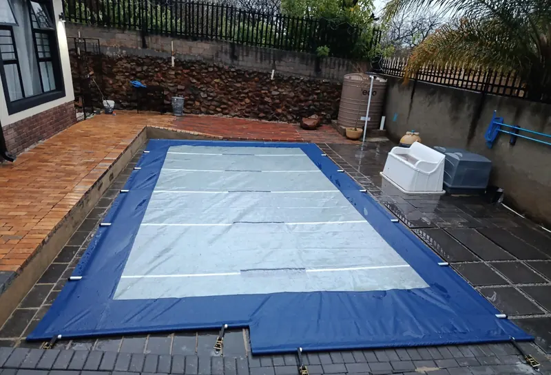 A navy cover with clear panels on dark paving