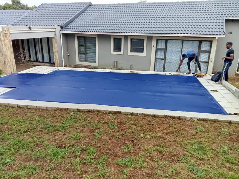 The team fitting a blue cover to a pool