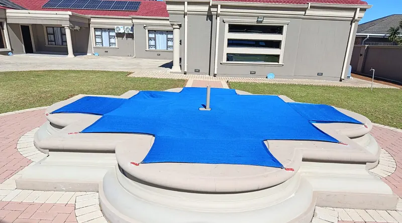 A blue woven mesh cover cut to a cross-shaped pool