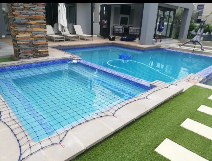 A safety net over a pool beside artificial grass