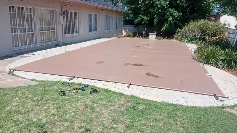 A brown PVC cover on a pool edged with lawn