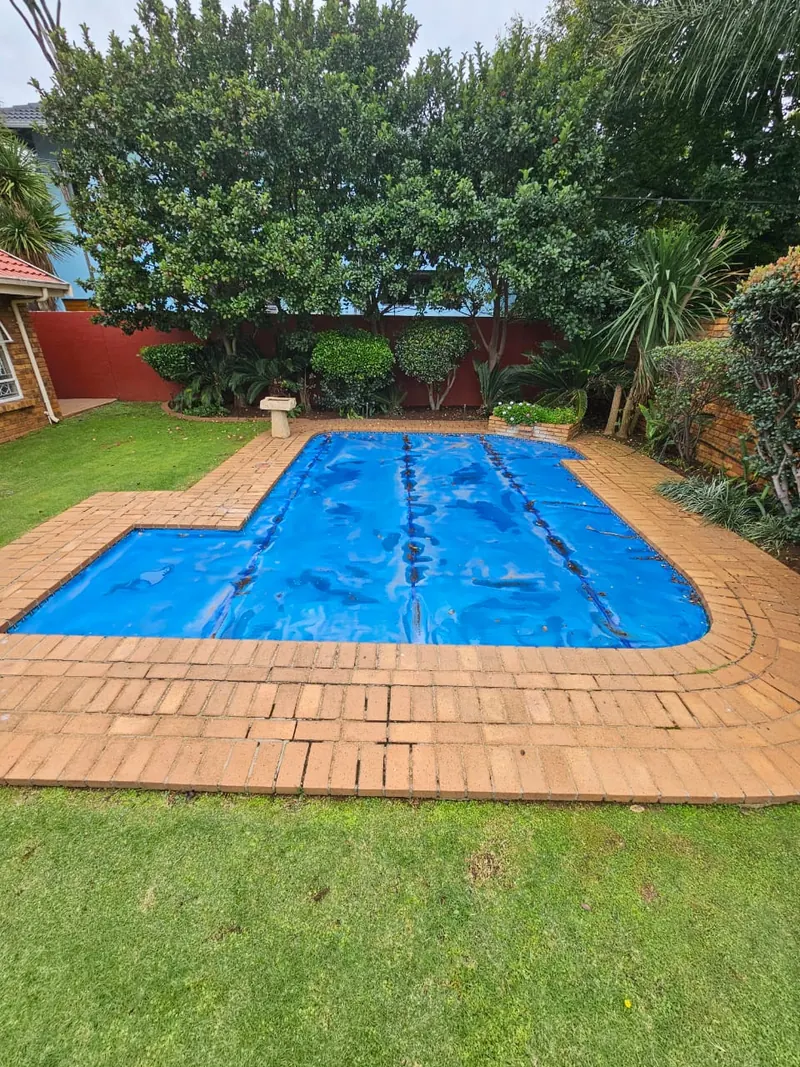 A blue solar blanket on an L-shaped pool