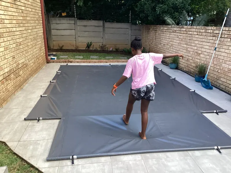 A child walking across a fitted grey PVC cover